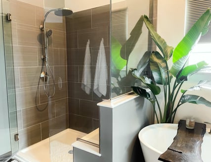 Dark grey tile with light grout, glass shower door, and shower bench